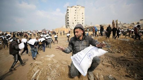 Palestinians carry bags of flour they grabbed from an aid truck near an Israeli checkpoint in Gaza City