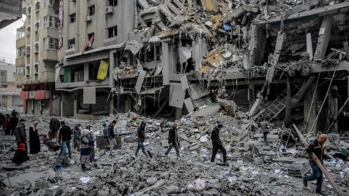 Palestinians walk amid the rubble of destroyed houses in Gaza